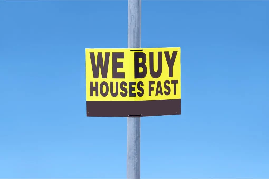 Sign stuck to a pole, reading "we buy houses fast."